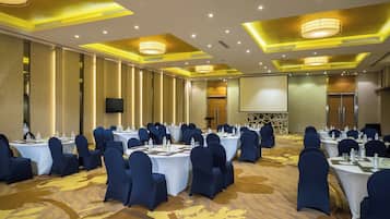 A conference room with round tables, blue chairs, and a large screen.