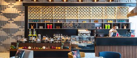 Eine moderne Bar mit vielfältigen Getränken und Snacks, Holzregalen und einer Wand mit Muster.