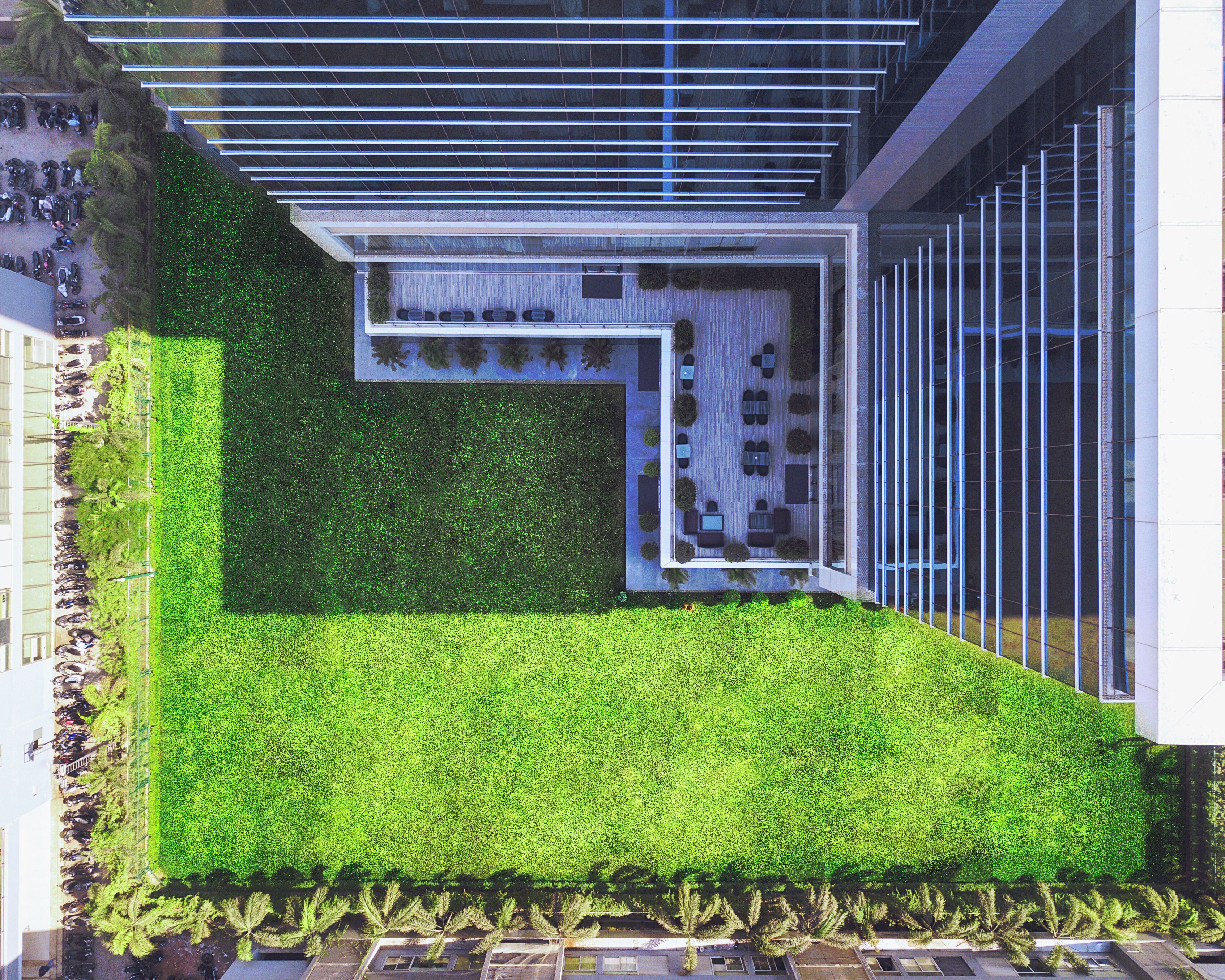 A modern building with a rooftop terrace featuring a green lawn and seating area.