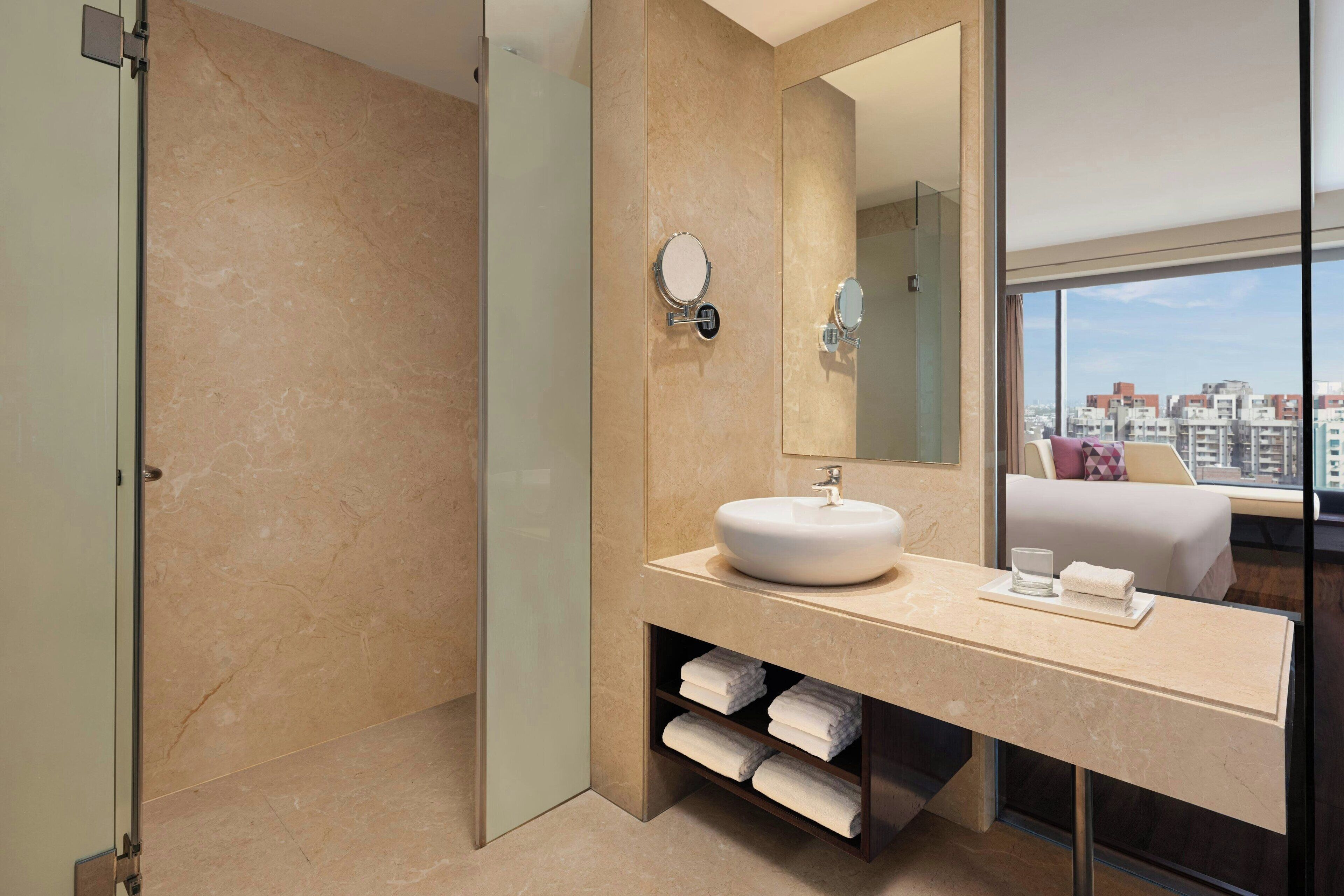 A modern bathroom with a large mirror, a round sink, and a glass-enclosed shower.