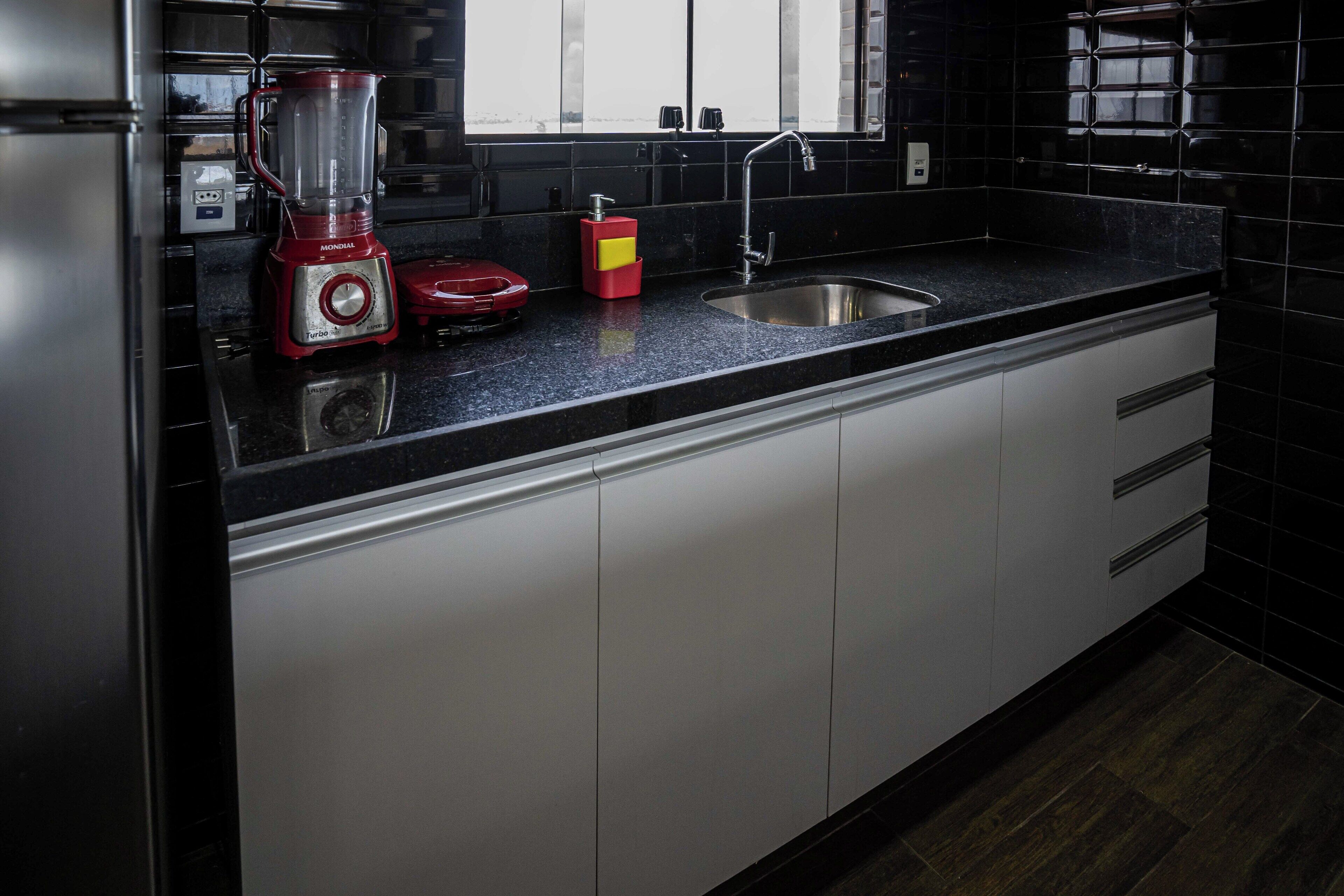 A modern kitchen with a black countertop, stainless steel appliances, and a window above the sink.