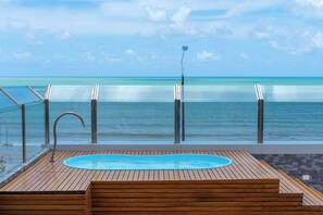 A wooden deck with a pool, overlooking a beach with clear turquoise water and a calm sea. - Bessa Golden Flats (João Pessoa)