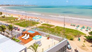 A beach resort with a pool area, lounge chairs, and umbrellas. - Bessa Golden Flats (João Pessoa)