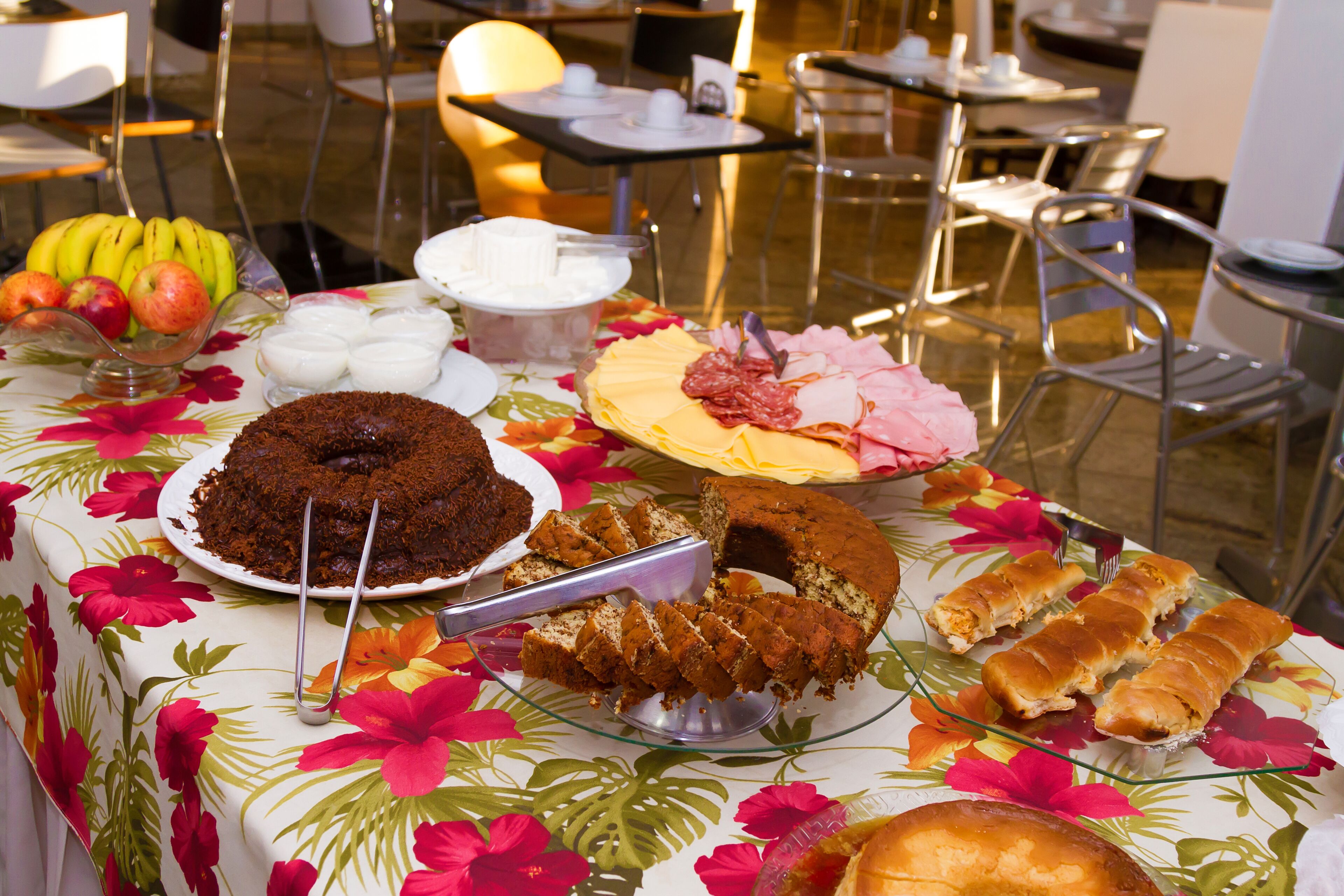 A buffet table with various food items including cakes, bread, and fruits.