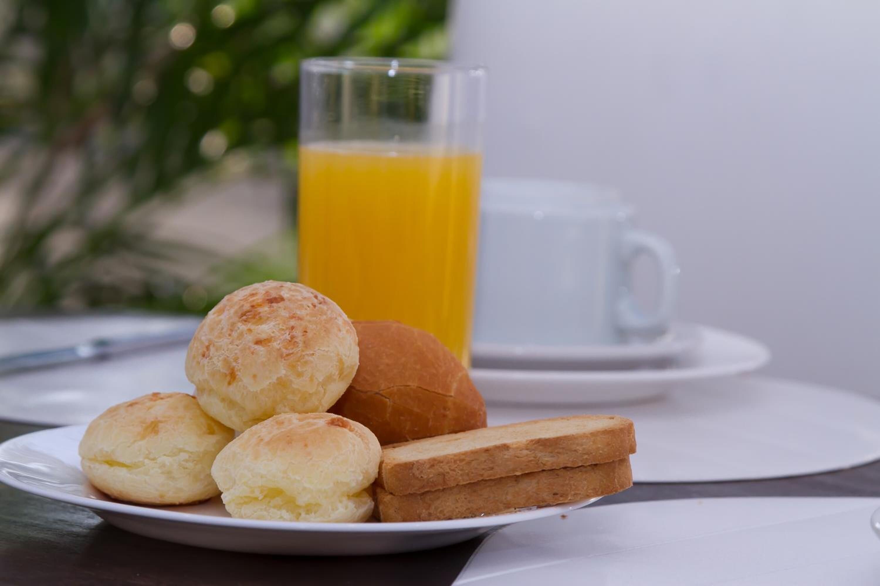 A plate with bread rolls and a glass of orange juice on a table.