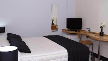 Hotelkamer met een bed, een bureau, een stoel, een televisie en een tafeltje met een plant en een snack.