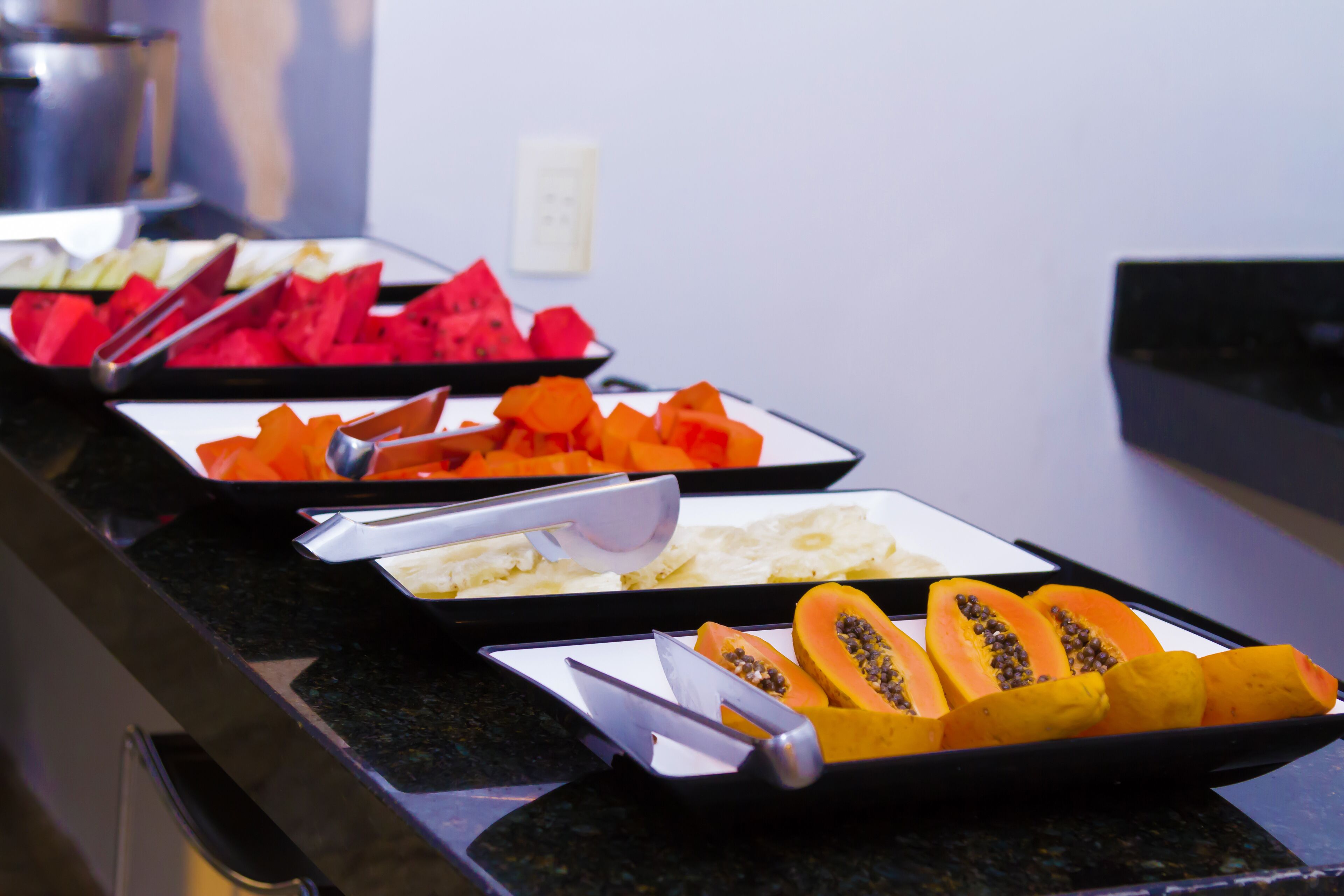 Un buffet con diversi tipi di frutta, come anguria, papaya e ananas.