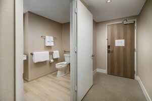 Un baño moderno con inodoro, perchero para toallas y puerta de madera.