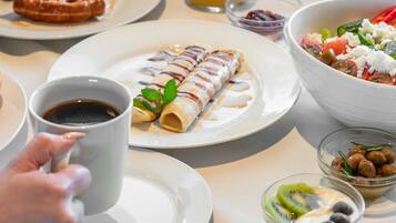 Un desayuno con platos de comida, un vaso de zumo de naranja y una taza de café.