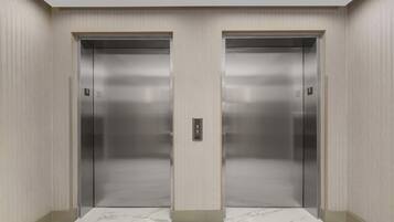 Deux portes d’ascenseur à la finition métallique, avec un panneau de commande situé au centre.