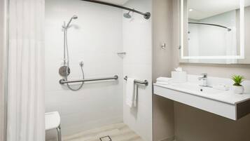 Un baño moderno con ducha, inodoro y lavabo con espejo.