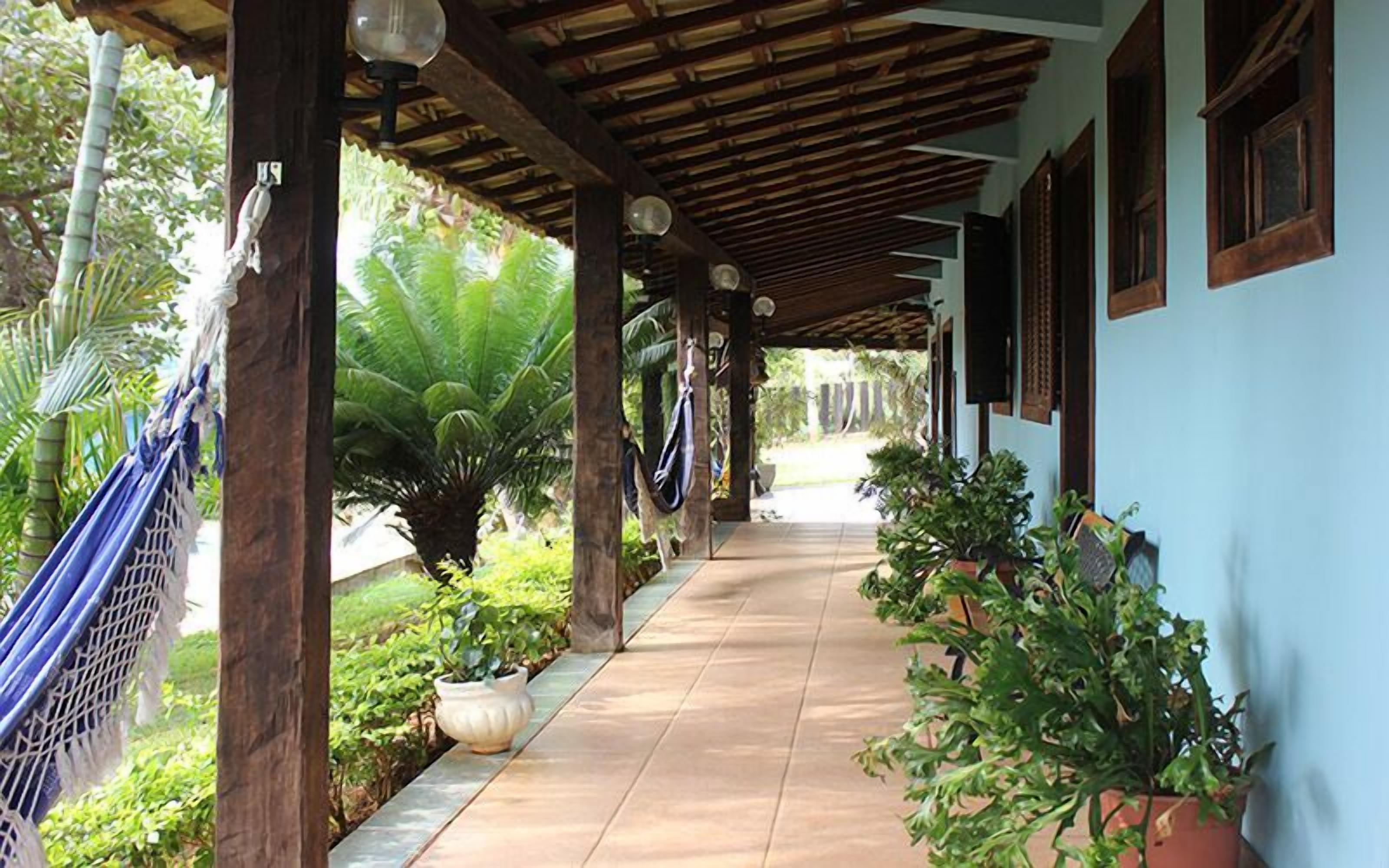 A covered outdoor area with a tiled walkway, wooden beams, and potted plants.