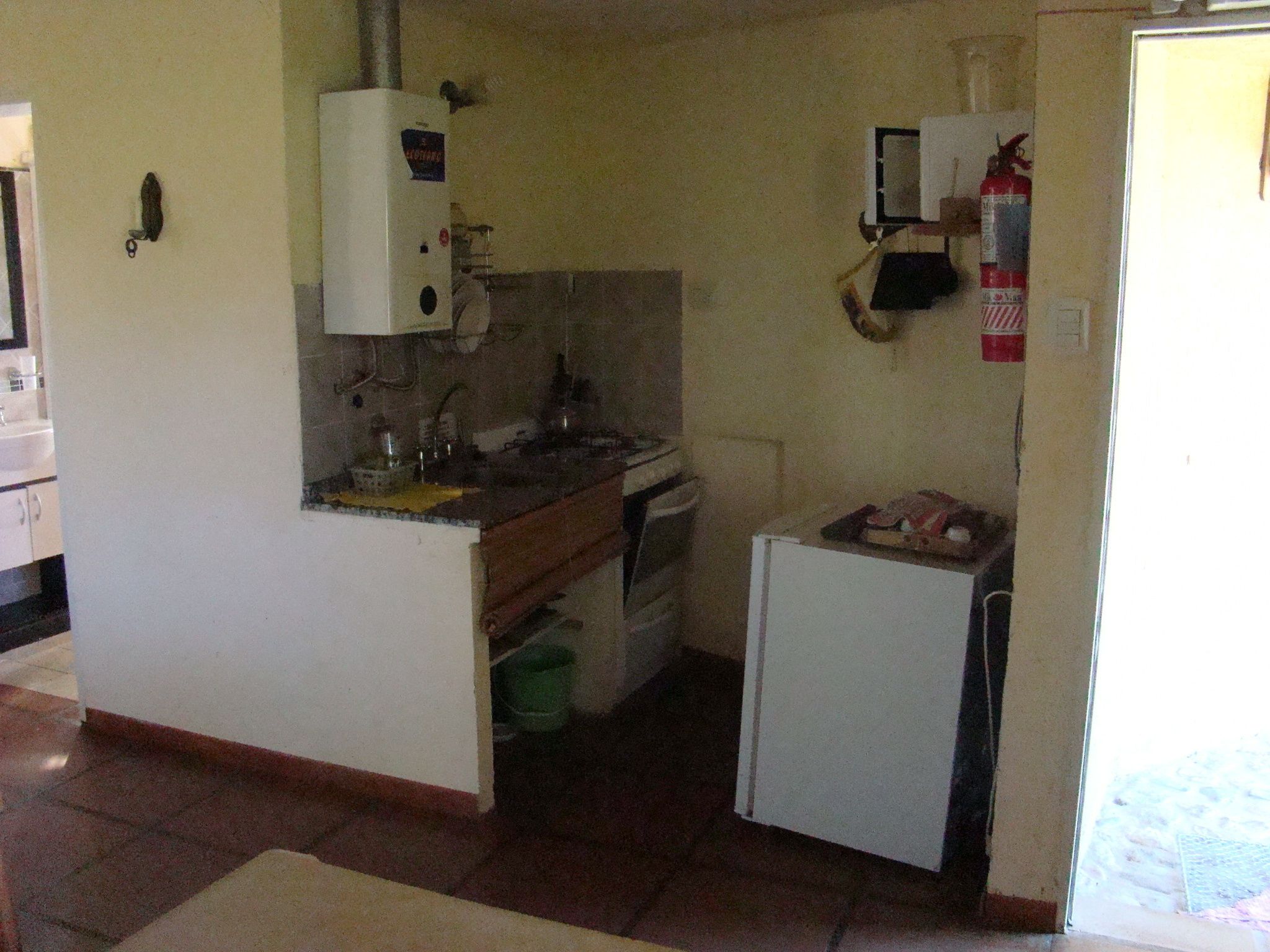 Cocina compacta con refrigerador, estufa, pileta y una pequeña mesada.