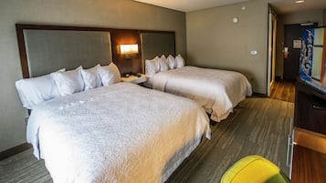 A hotel room with two beds, a bedside table, a lamp, and a television.
