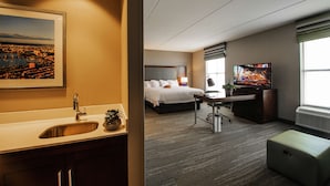 A hotel room with a bed, desk, TV, and a painting of a cityscape. - Hampton Inn & Suites Foxborough/Mansfield (Foxborough)