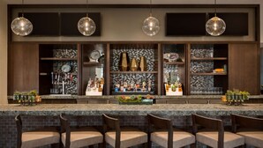 A bar area with a granite countertop, multiple bar stools, and hanging pendant lights. - Embassy Suites by Hilton San Antonio Landmark (San Antonio)