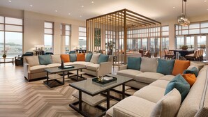 A spacious living area with a large sectional sofa, multiple coffee tables, and a wooden partition. - Embassy Suites by Hilton San Antonio Landmark (San Antonio)