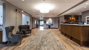 A hotel lobby with a reception desk, seating area, and a wooden floor. - Hampton Inn & Suites St. George, UT (St. George)