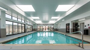 A swimming pool with clear water, surrounded by windows and a tiled floor. - Hampton Inn & Suites St. George, UT (St. George)