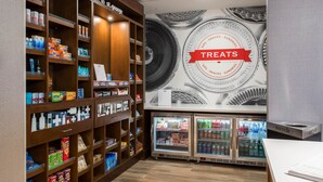 A snack and treat section with shelves stocked with various snacks, a wall mural, and two beverage refrigerators. - Hampton Inn & Suites St. George, UT (St. George)