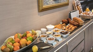 Um buffet de café da manhã com frutas, doces e bebidas.