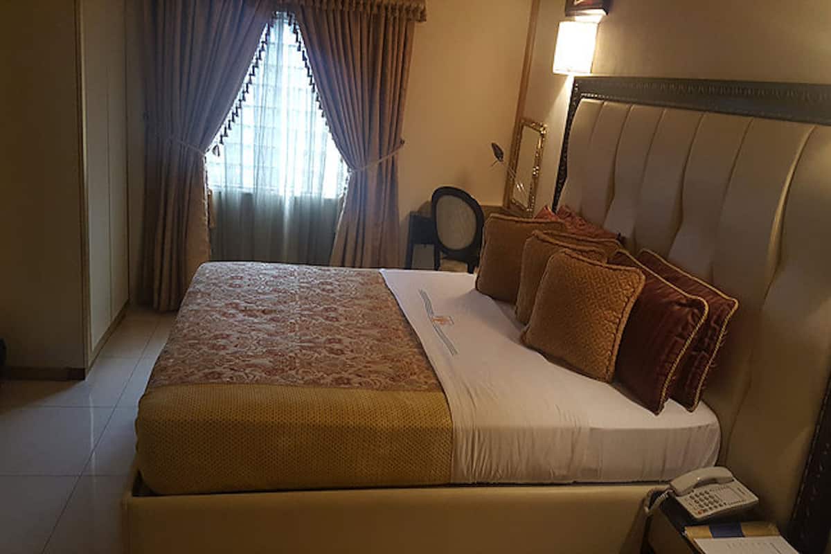 A hotel room with a large bed, a bedside telephone, and a chair.