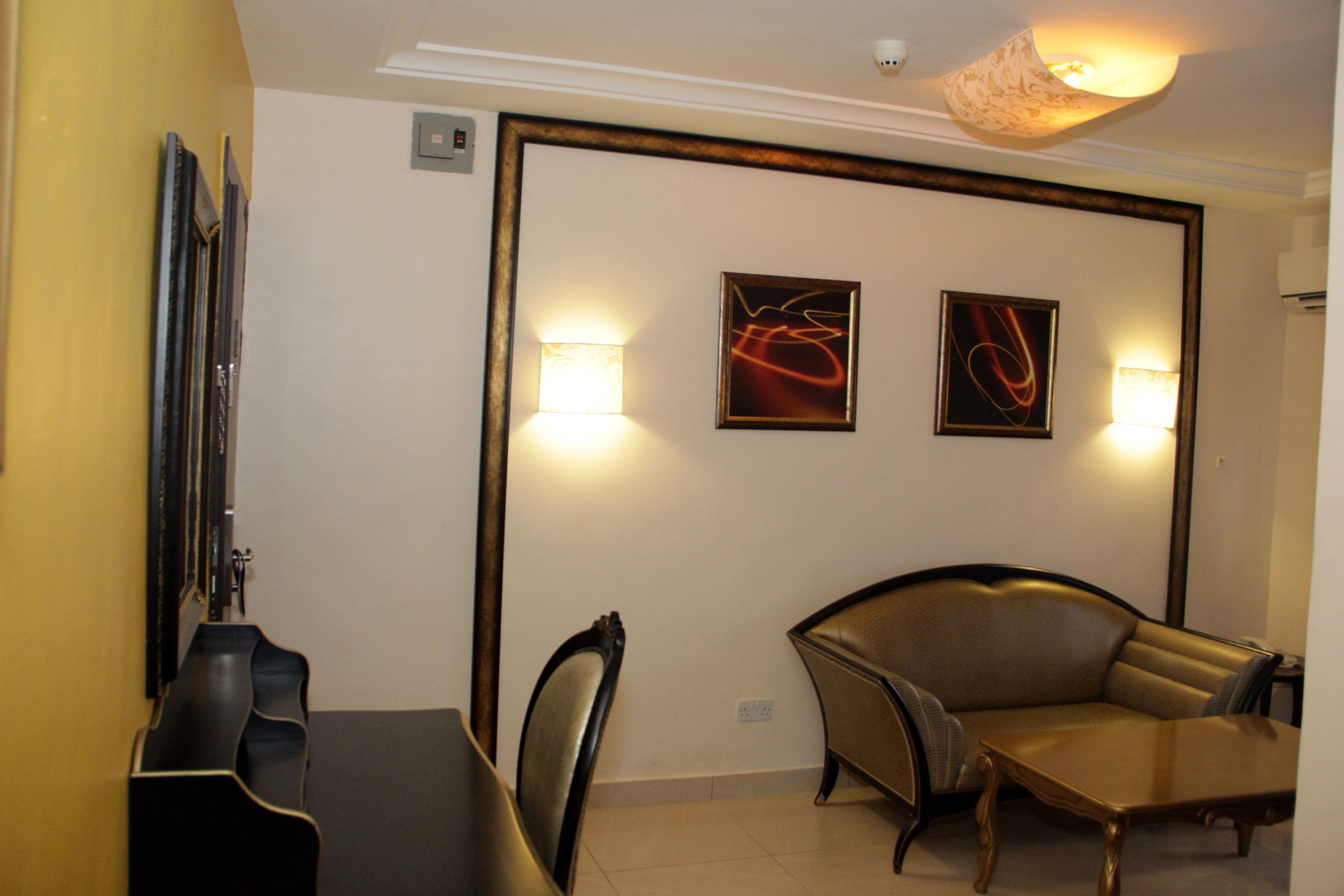 Un espace repas comprenant une table et des chaises, un canapé et deux lampes fixées au mur.
