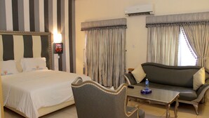 A hotel room with a bed, a sofa, a chair, and a coffee table. - Calabar Harbour Resort SPA (Calabar)
