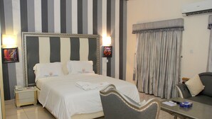 A hotel room with a large bed, bedside tables, a desk, and a chair. - Calabar Harbour Resort SPA (Calabar)