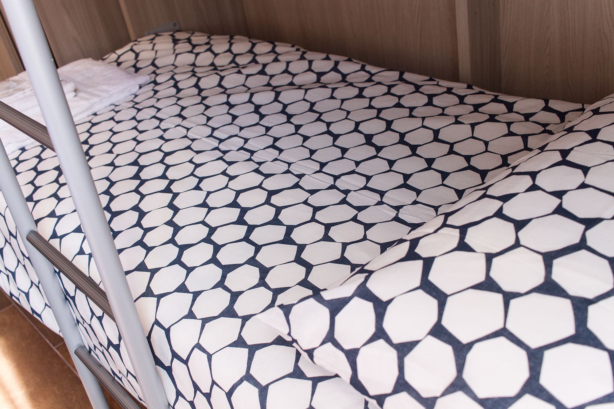A bunk bed with a patterned mattress and metal railings.