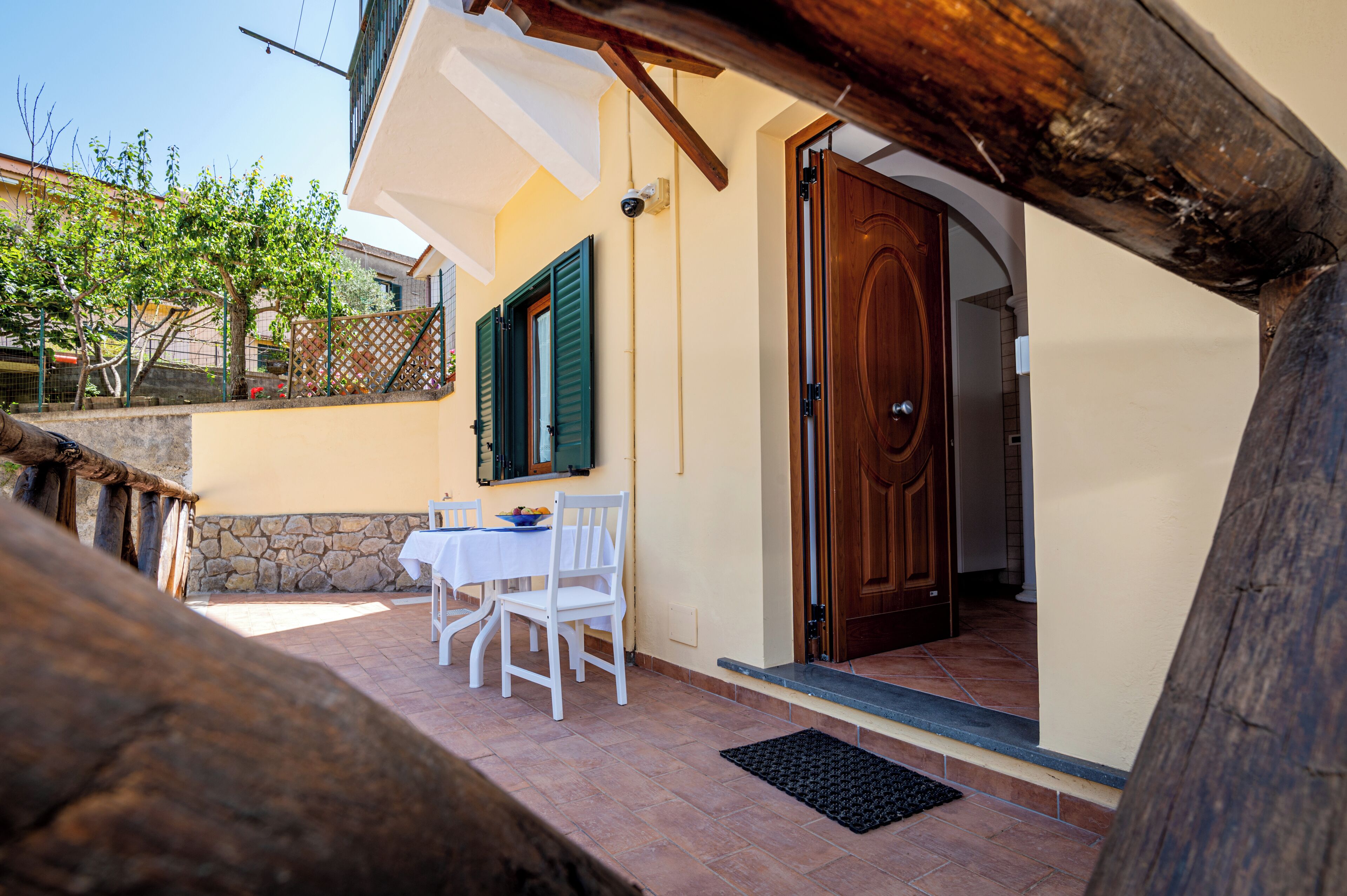 Une terrasse avec une table et des chaises, une porte en bois et un mur en pierre.