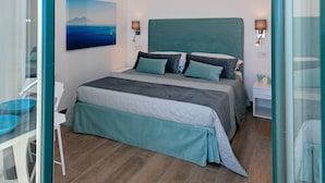 A modern bedroom with a large bed, a painting on the wall, and a view of the sea. - Maison Cipriani (Massa Lubrense)