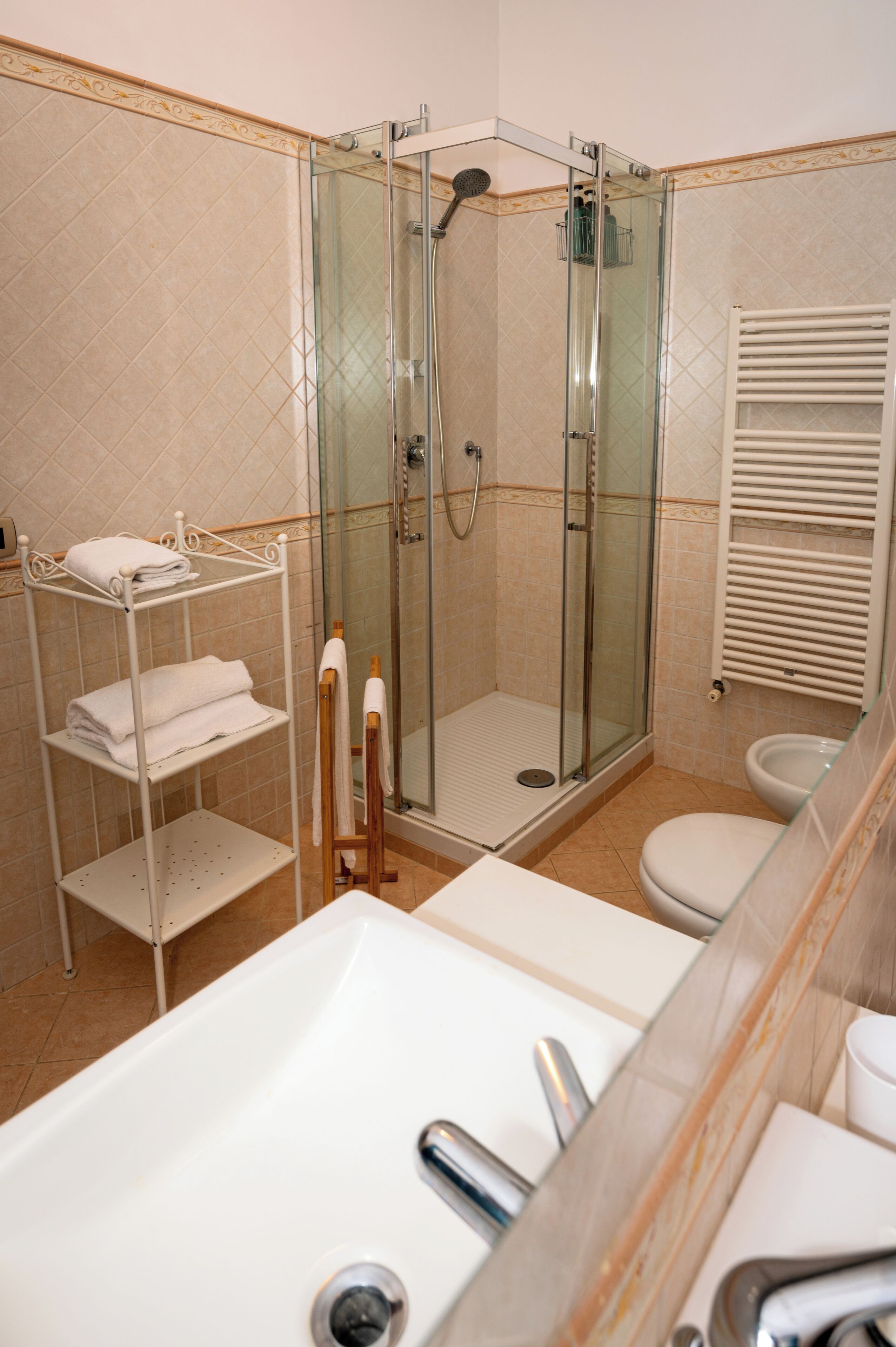 Ein modernes Badezimmer mit einer gläsernen Duschkabine, einem weißen Waschbecken und einer Toilette.