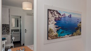 A modern kitchen with white cabinets, a countertop, and a hanging light fixture. - Maison Cipriani (Massa Lubrense)