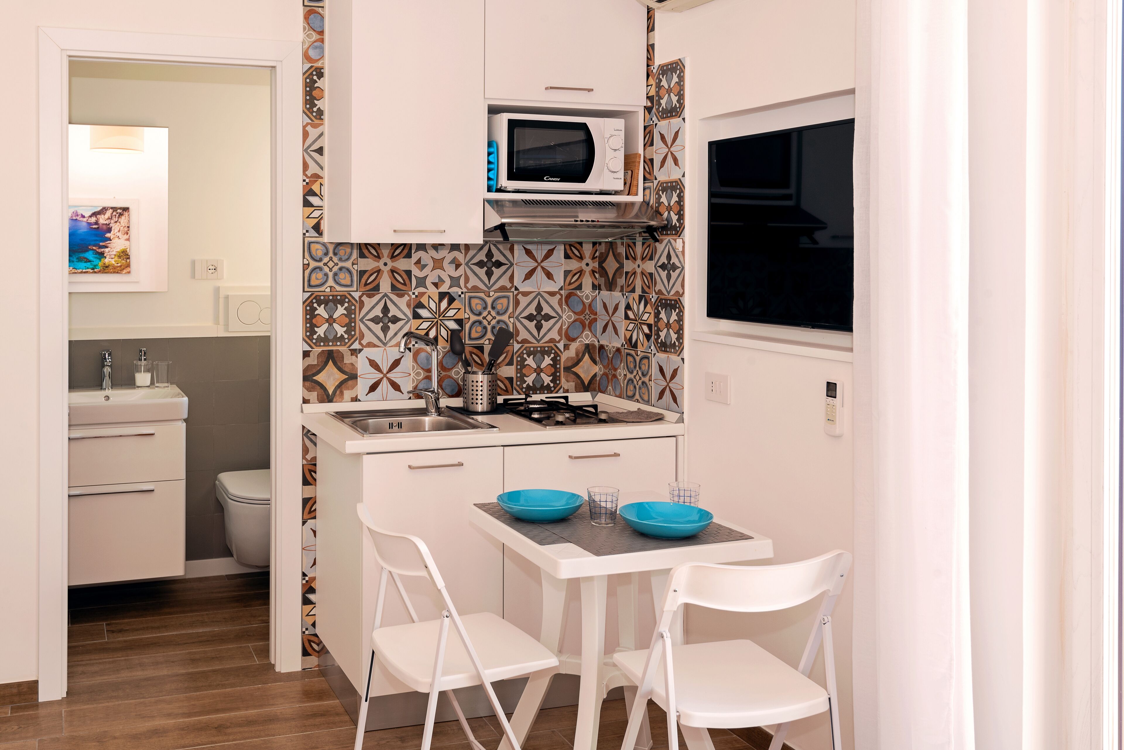 A compact kitchen with a microwave, sink, and a small dining area with two chairs.