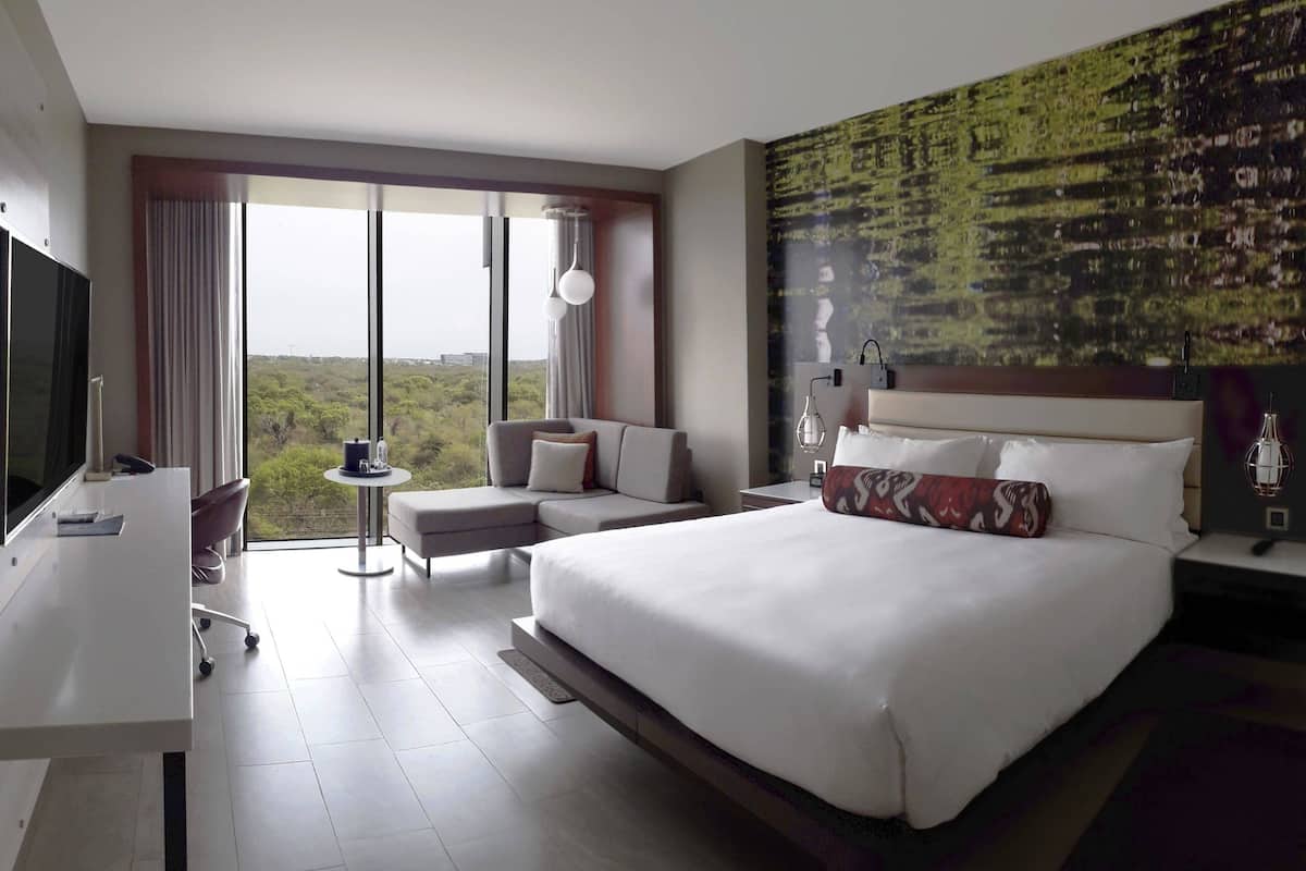 Una habitación de hotel moderna con una cama grande, un escritorio, un sofá y vistas al exterior.