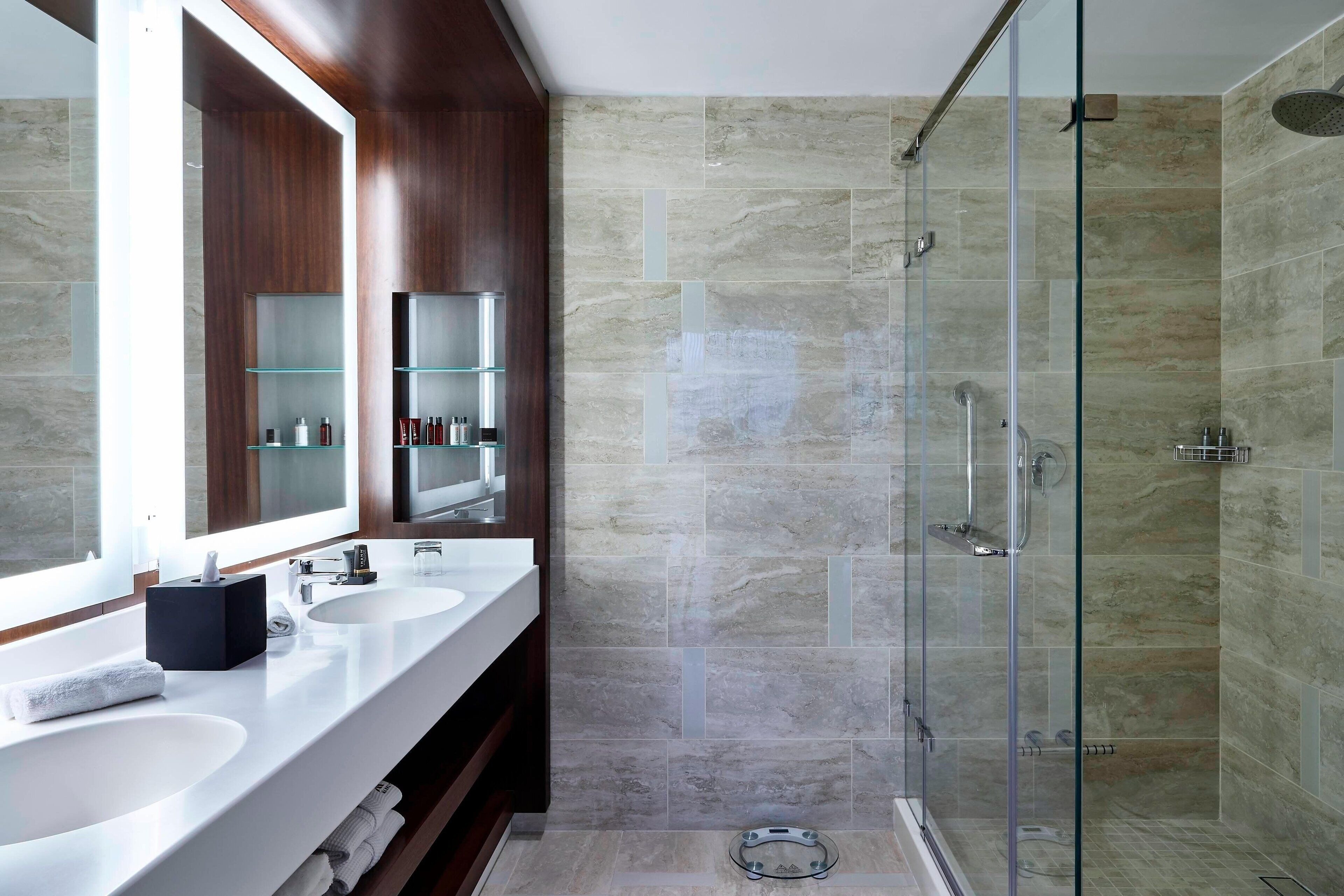 A modern bathroom with two sinks, a large mirror, and a glass-enclosed shower.