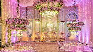 Une salle de banquet luxueuse, agrémentée de lustres somptueux, de compositions florales et d’une décoration de table élégante.