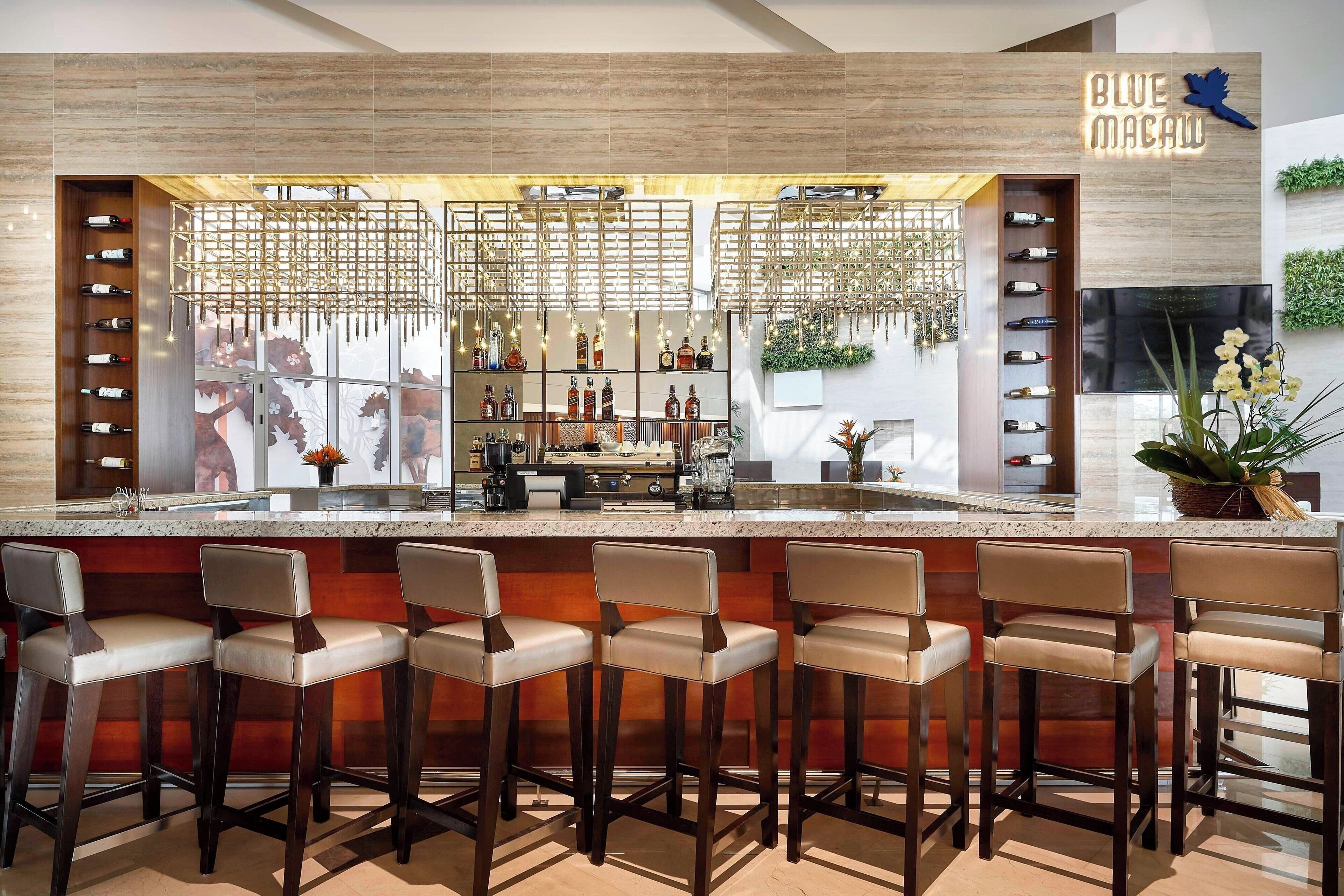 A bar area with a wooden bar counter, multiple wine bottles, and bar stools.