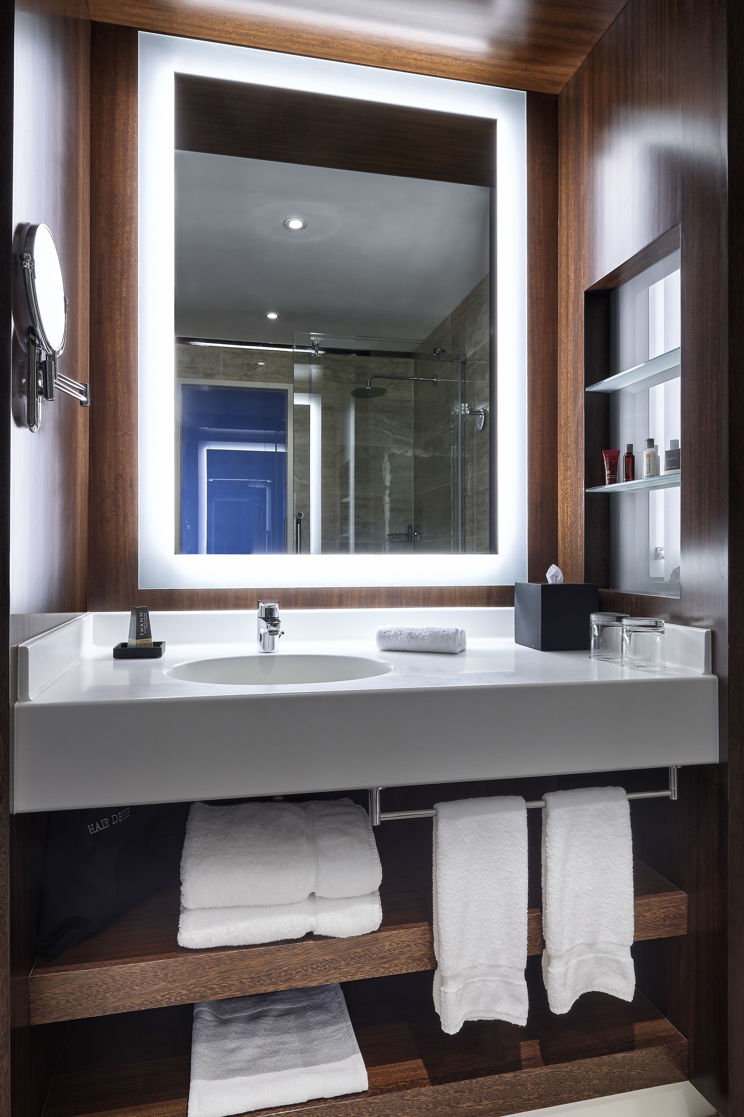 Un baño moderno con un espejo grande, dos lavamanos y una cabina de ducha de vidrio.