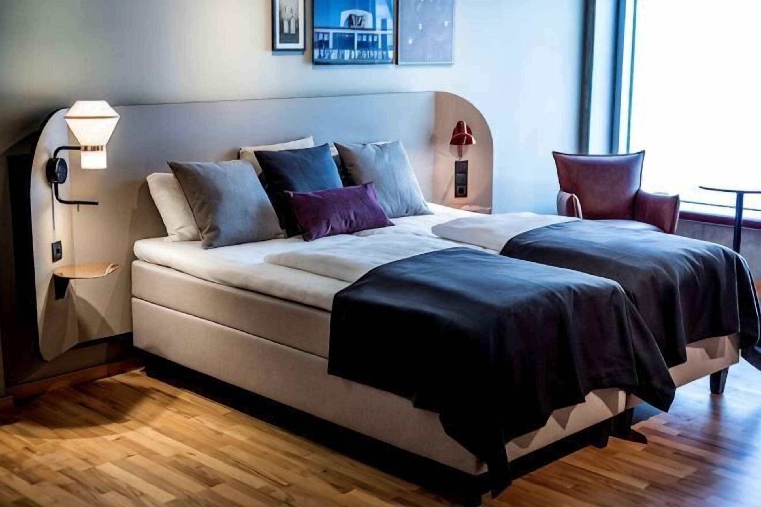 Een moderne hotelkamer met een groot bed, een nachtkastje met een lamp en een stoel.
