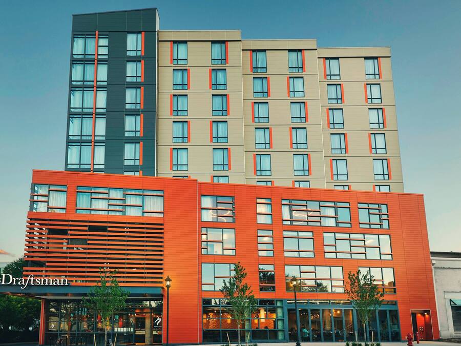 Een meerlaags hotel met een modern ontwerp, gekenmerkt door een opvallende oranje gevel en veel ramen.