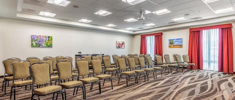 A conference room with rows of chairs, a patterned carpet, and artwork on the walls.