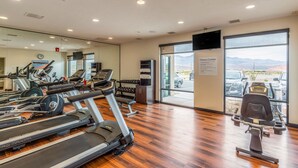 Una palestra con tapis roulant, cyclette e una panca per pesi.