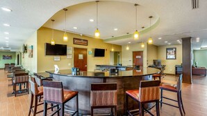 A bar area with a curved counter, multiple bar stools, and hanging pendant lights.