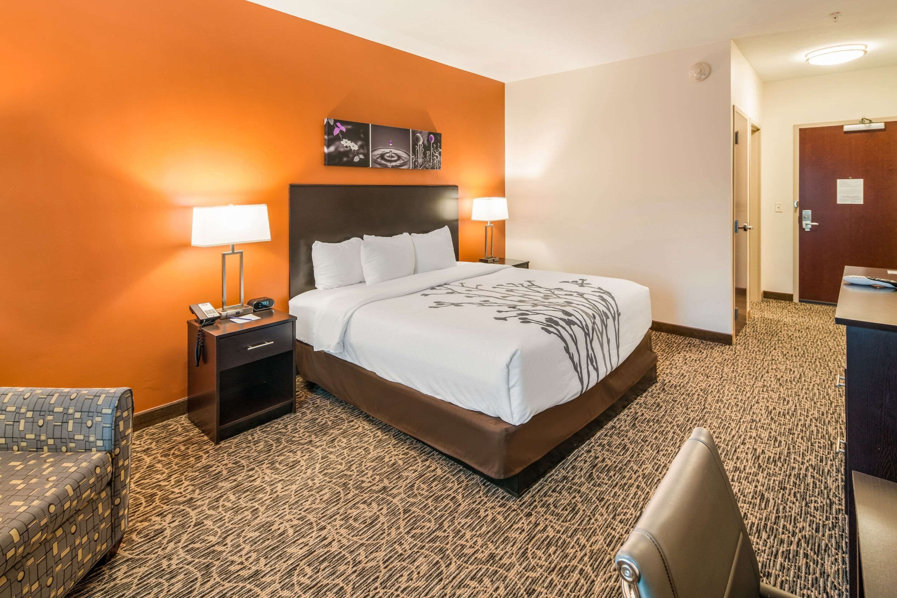 A hotel room with a large bed, two bedside tables with lamps, a small desk, and a chair.