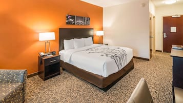 A hotel room with a large bed, two bedside tables with lamps, a small desk, and a chair.