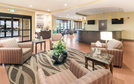 A lobby with seating areas, a reception desk, and a view of the outside.