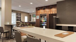 A modern hotel lobby with a long reception desk, seating area, and a Starbucks coffee machine.