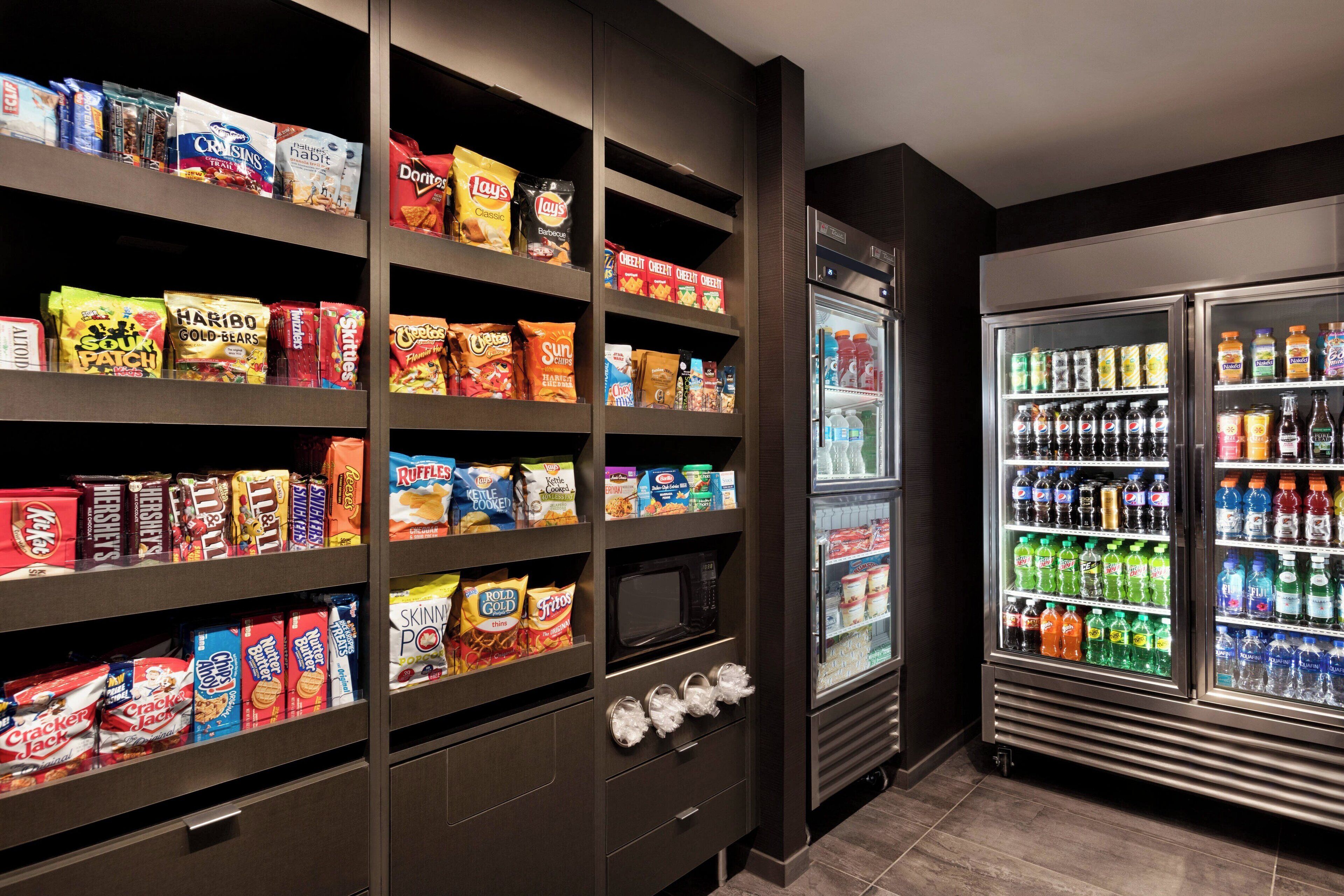 Exposição de petiscos e bebidas, com diversas opções de lanches e refrigerantes embalados.